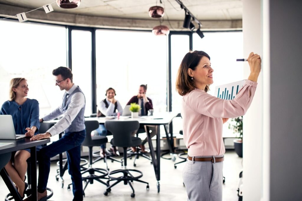 businesspeople working in an office writing on whiteboard e1669185171296